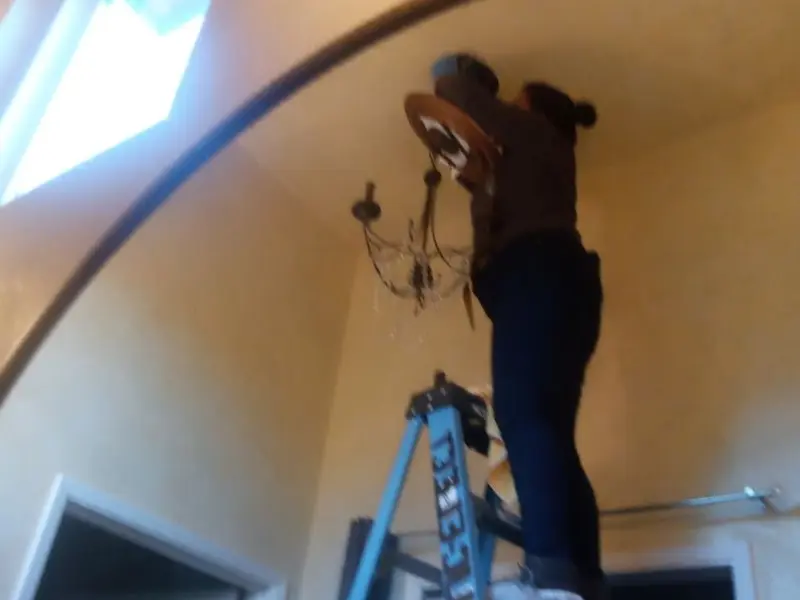 Electrician installing a chandelier in a Woodhull residence